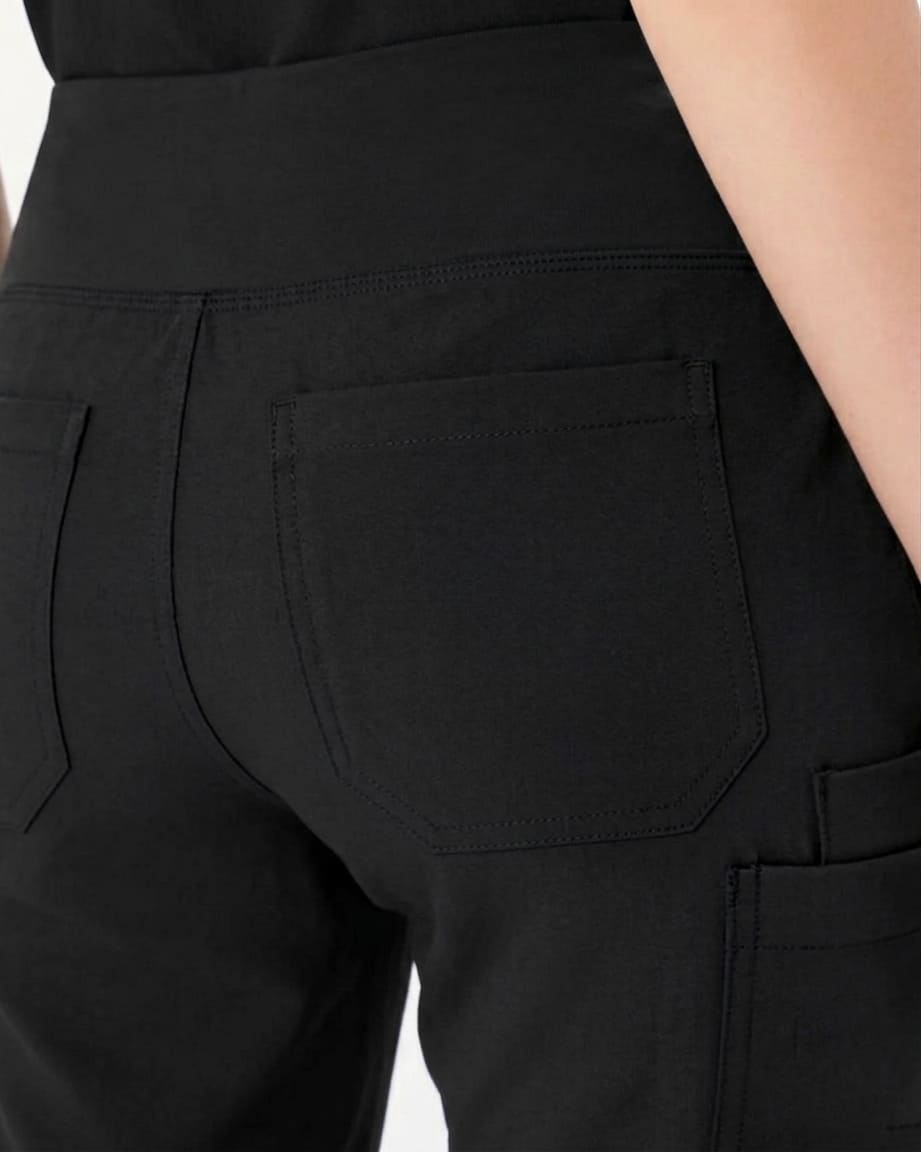 Close-up of the back waistband and rear pocket area of black pants, with part of a model's leg visible on the right side.