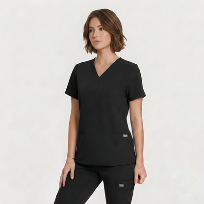 A woman modeling a black V-neck scrub top and matching black scrub pants against a clean white studio background.