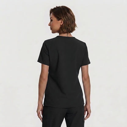 A woman with short brown hair is shown from the back wearing a plain black short-sleeve crewneck top and black pants against a light gray studio background.