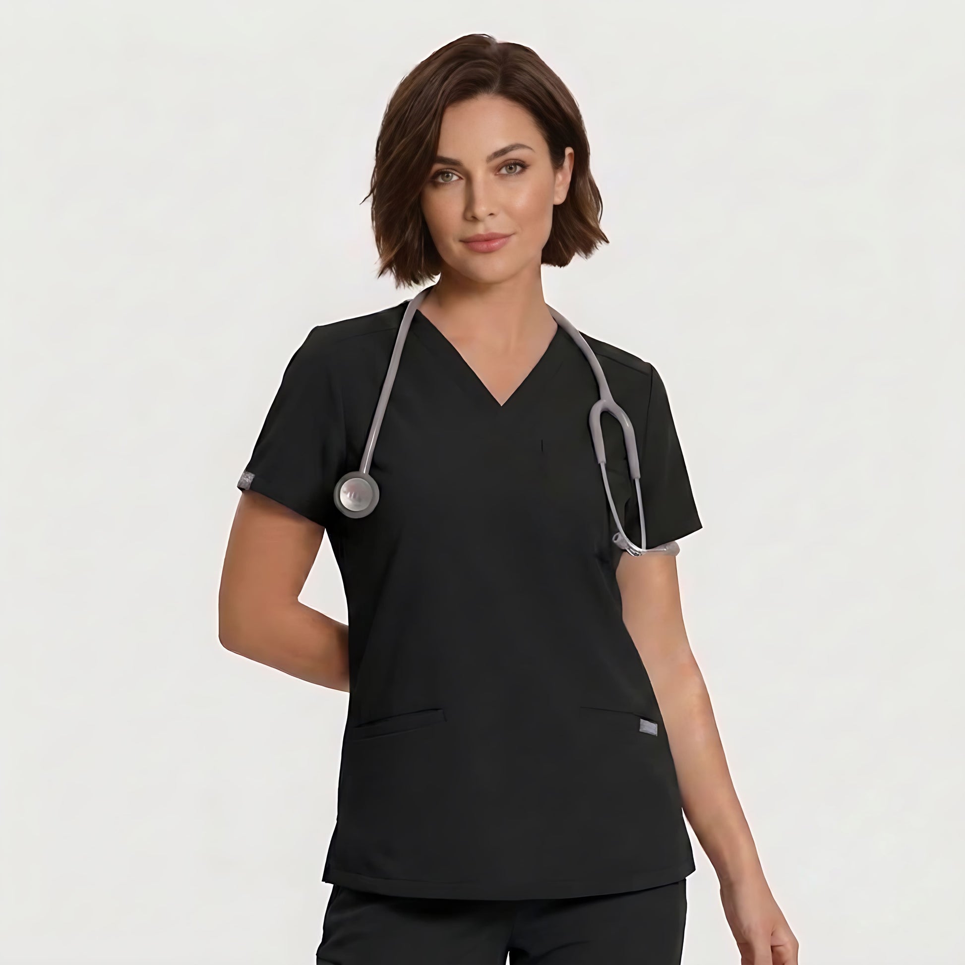 A woman wearing a black V-neck scrub top with a gray stethoscope around her neck, photographed against a clean light gray studio background.