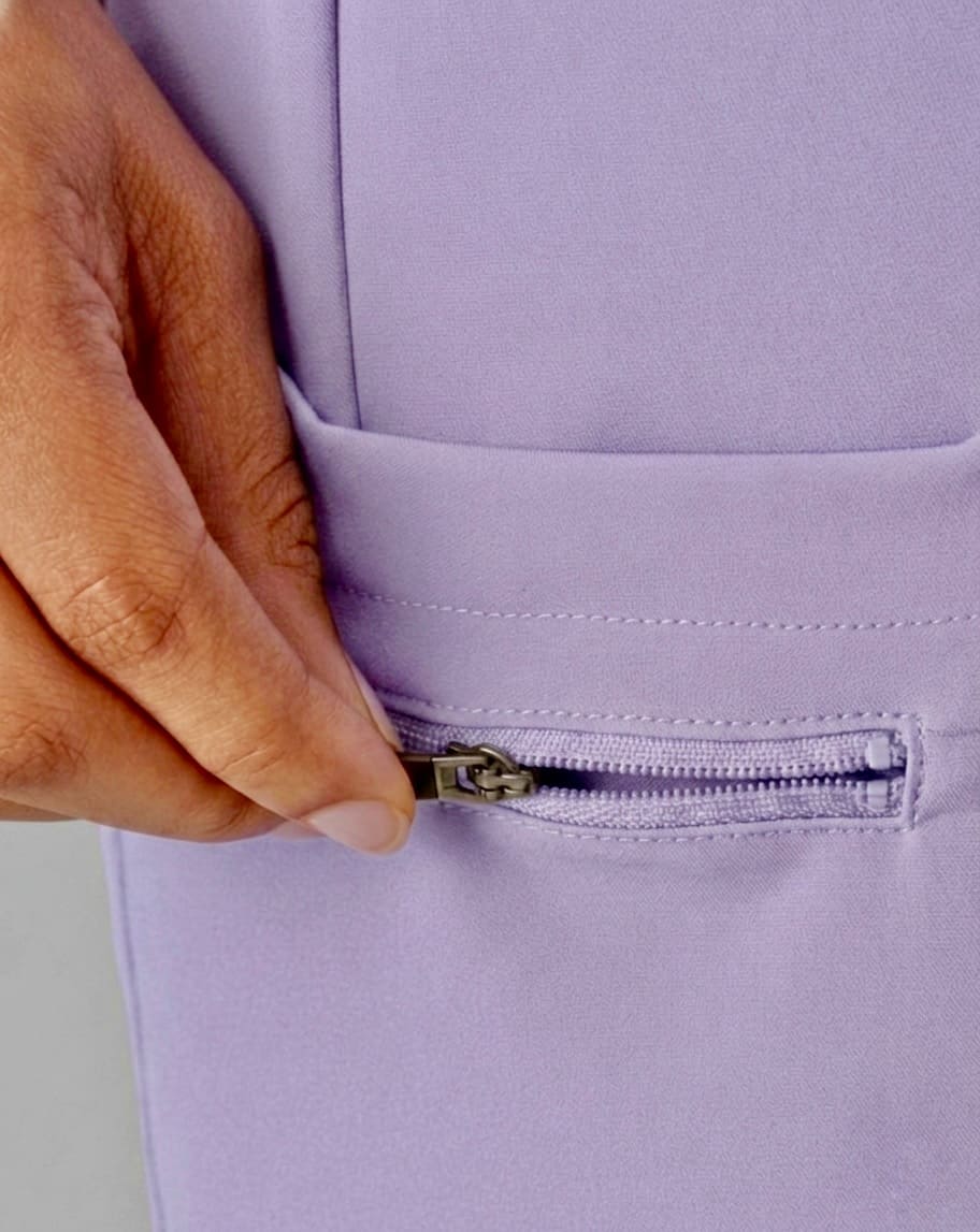 Hand zipping a lavender garment with a plain background