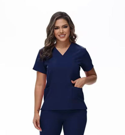 A woman wearing a navy V-neck scrub top with three pockets.