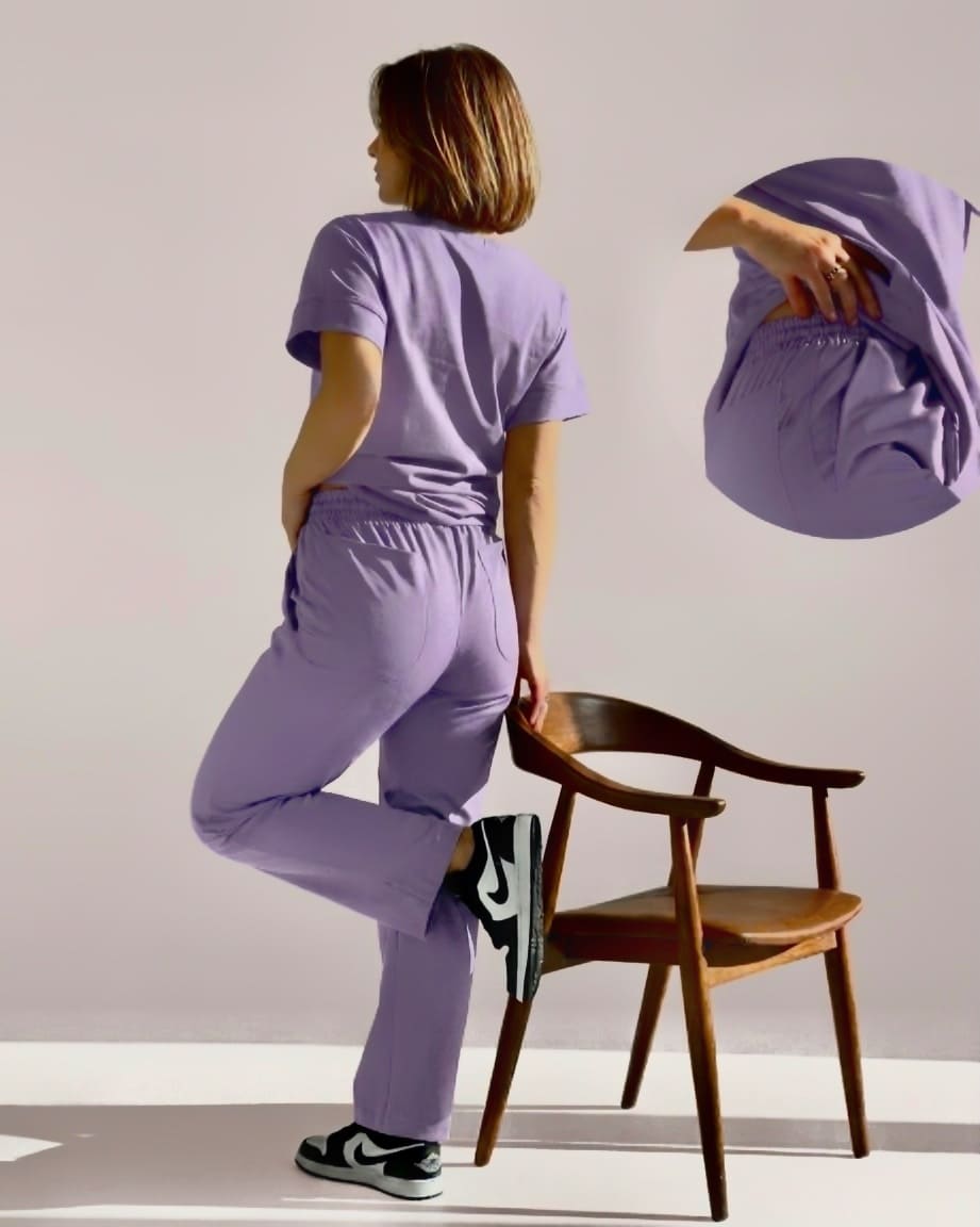 Person wearing a purple outfit with a wooden chair in the background