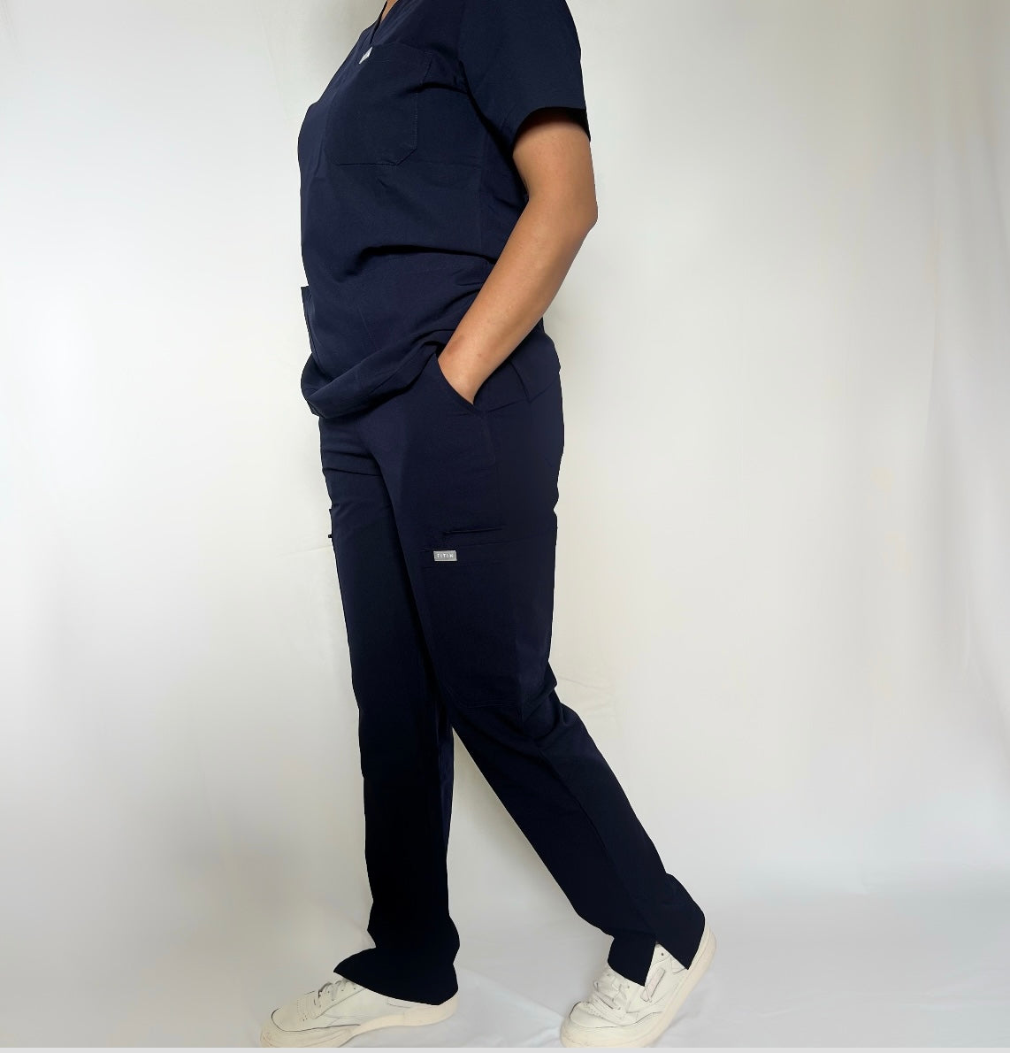 Fitix navy scrub with multiple pockets wearing by a nurse in a clean white background.