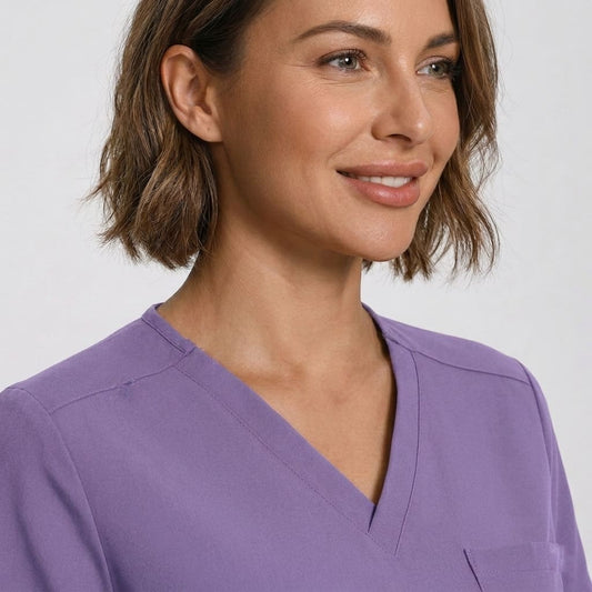 Woman wearing a purple scrub top against a plain background