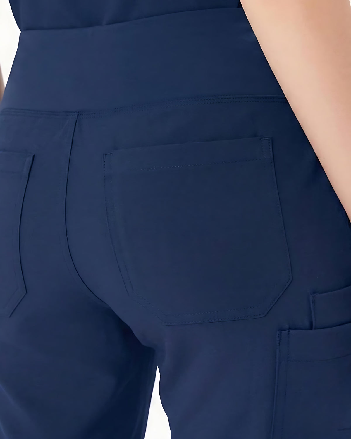 Close-up of the back waist and pockets of navy blue scrub pants worn by a model.