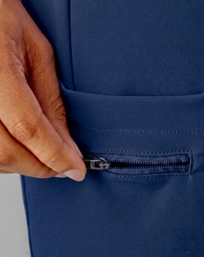 Close-up of a hand unzipping a front pocket on a navy blue garment, showing the fabric texture and zipper detail.