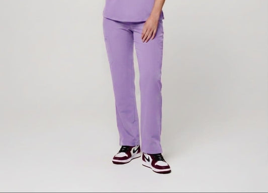 Person wearing a purple scrub set on a plain background