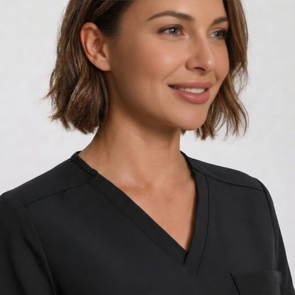 A close-up of a woman wearing a black V-neck scrub top against a light gray background.