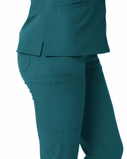 Close-up of a person wearing teal scrub top and matching scrub pants, showing the side and back pockets against a plain white background.
